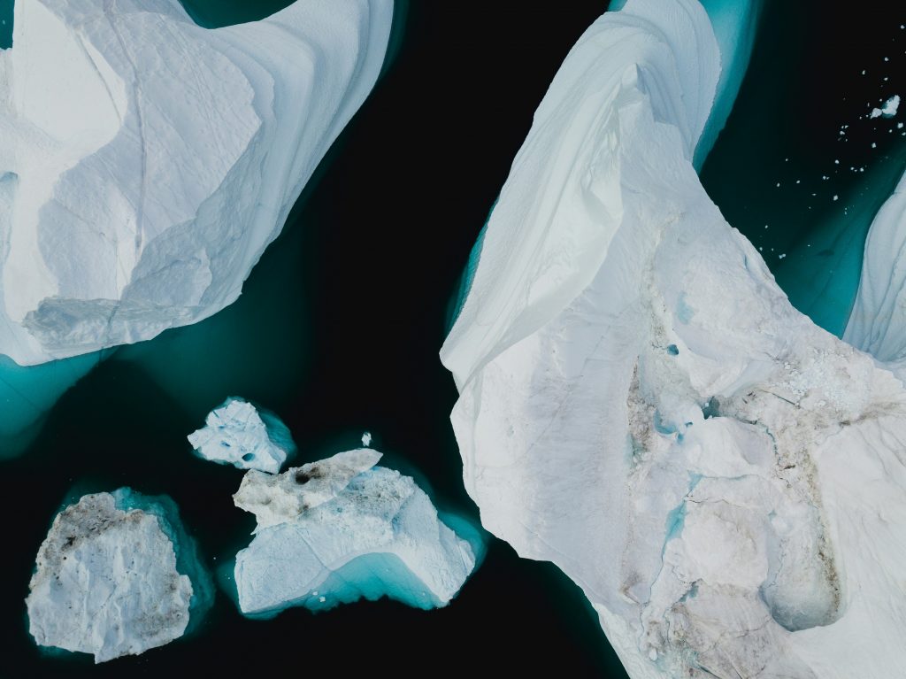 Aerial view of blue, abstract glaciers and icy waters in an ocean.
